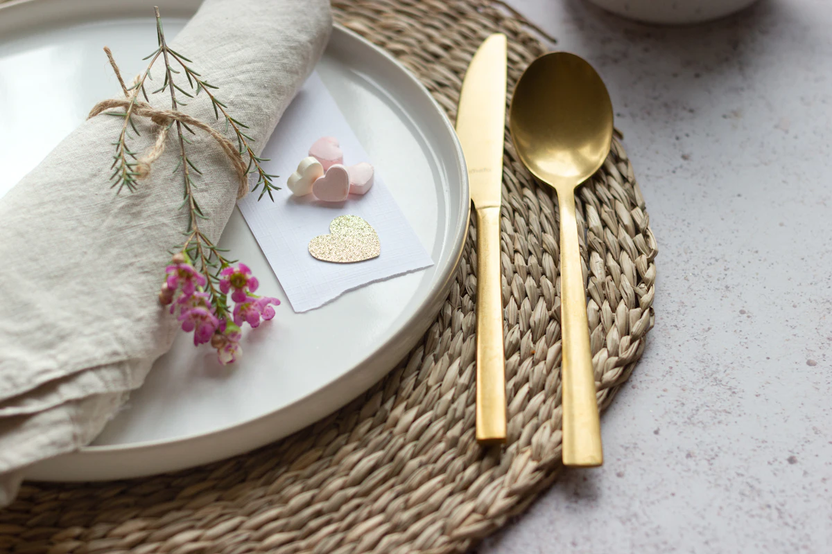 A place setting: linen napkin tied with a sprig, a gold knife and spoon